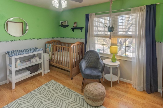 bedroom with a crib, baseboards, and wood finished floors