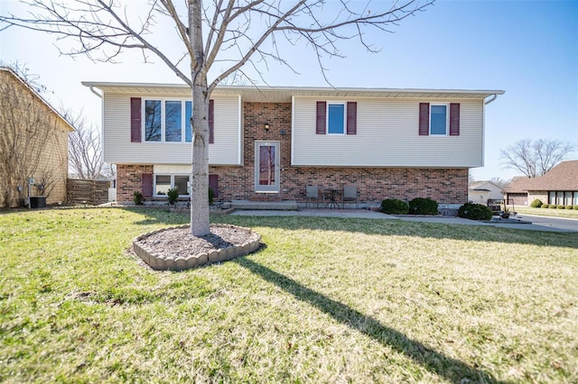 split foyer home featuring a front yard and brick siding