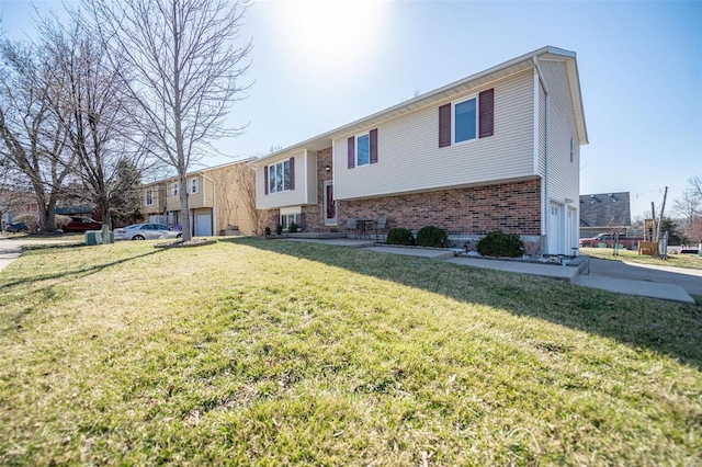 raised ranch featuring a front lawn, an attached garage, and brick siding