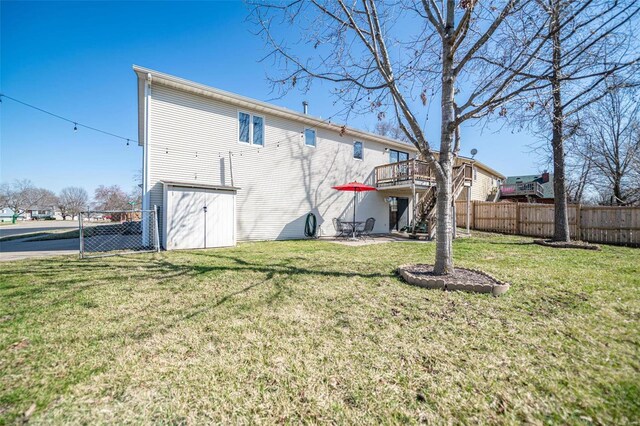 back of house with stairway, a lawn, a wooden deck, and fence