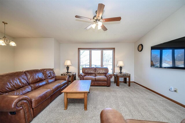 living room featuring ceiling fan with notable chandelier, light colored carpet, and baseboards
