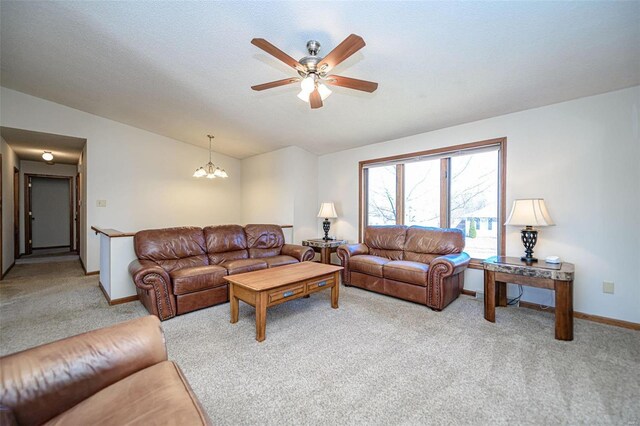 living area with vaulted ceiling, ceiling fan with notable chandelier, baseboards, and light carpet