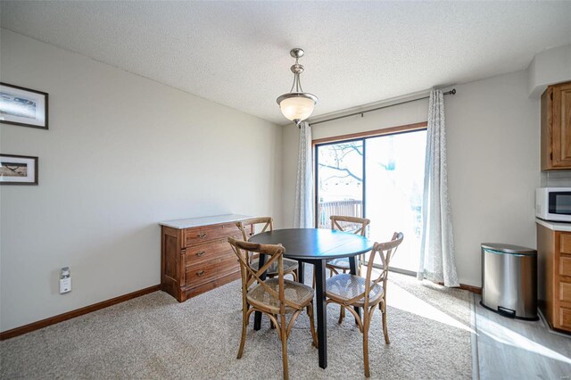 dining area featuring light carpet, a textured ceiling, and baseboards