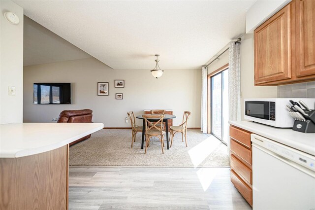 dining area with baseboards, light wood-style flooring, and vaulted ceiling