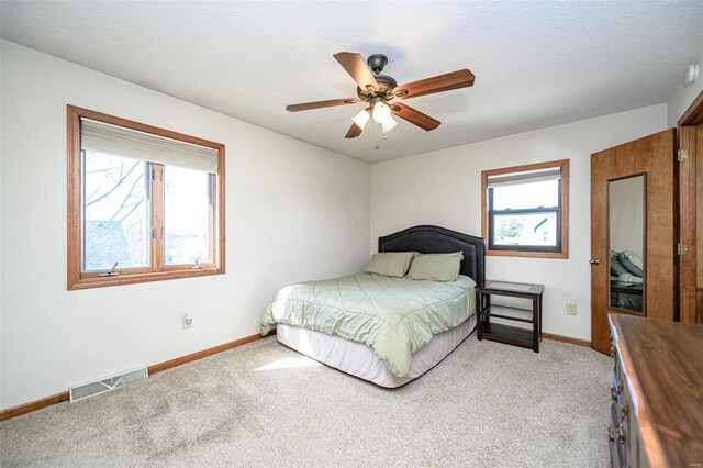 bedroom with visible vents, multiple windows, a textured ceiling, and light colored carpet