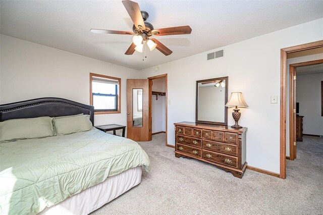 carpeted bedroom with a ceiling fan, baseboards, visible vents, and a textured ceiling