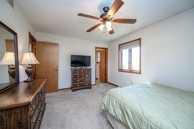 bedroom with visible vents, light colored carpet, a textured ceiling, and baseboards