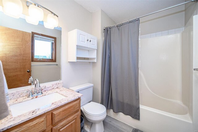 full bath featuring vanity, wood finished floors, shower / bath combo with shower curtain, a textured ceiling, and toilet