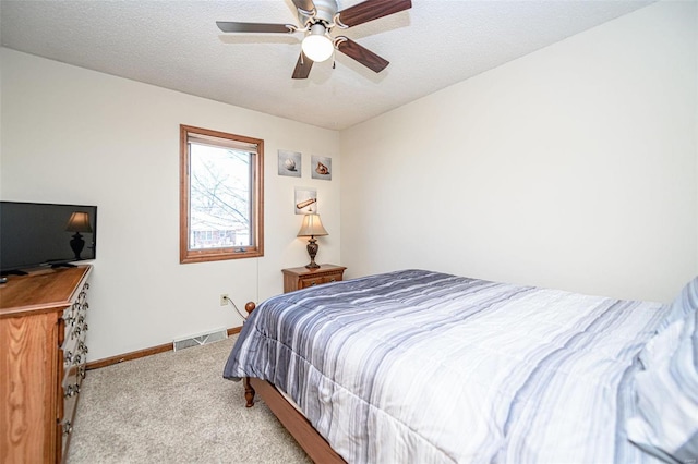 bedroom with visible vents, a textured ceiling, carpet floors, baseboards, and ceiling fan
