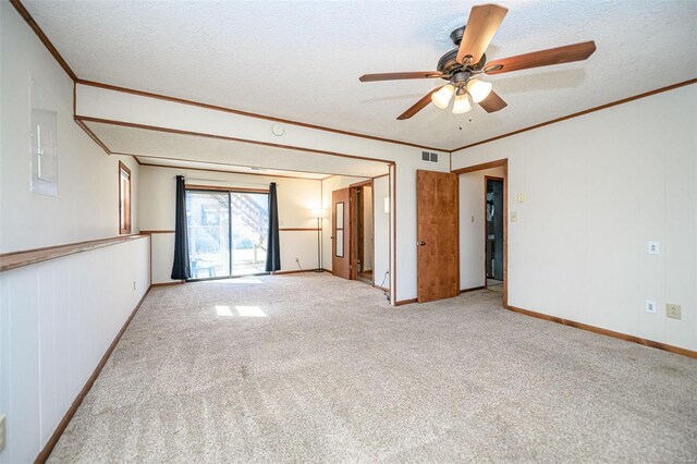carpeted spare room with visible vents, a textured ceiling, ceiling fan, and ornamental molding