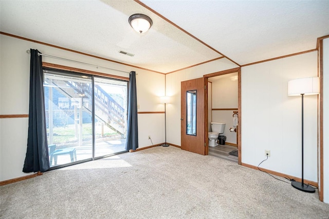 spare room with visible vents, carpet flooring, a textured ceiling, and crown molding