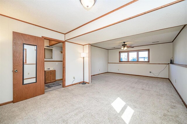 unfurnished room featuring ornamental molding, a textured ceiling, carpet flooring, baseboards, and ceiling fan