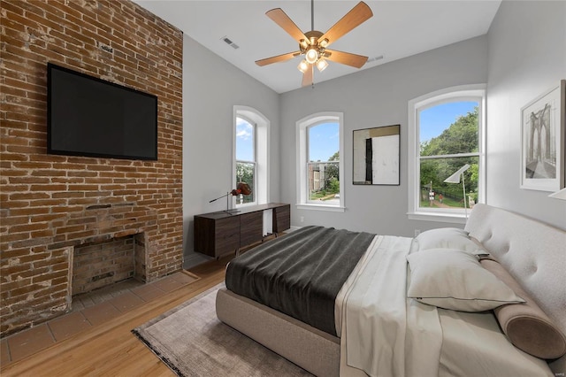 bedroom with vaulted ceiling, multiple windows, wood finished floors, and visible vents