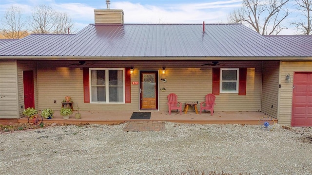 view of front facade featuring ceiling fan, metal roof, and a chimney