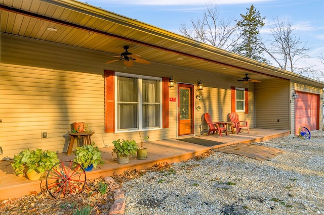 view of exterior entry with an attached garage, covered porch, and a ceiling fan