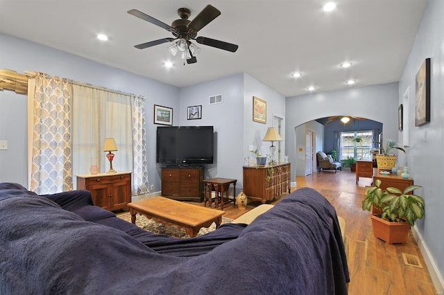 living room with wood finished floors, arched walkways, visible vents, and ceiling fan