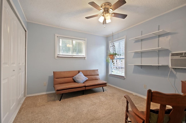 sitting room with a ceiling fan, a textured ceiling, crown molding, baseboards, and light colored carpet