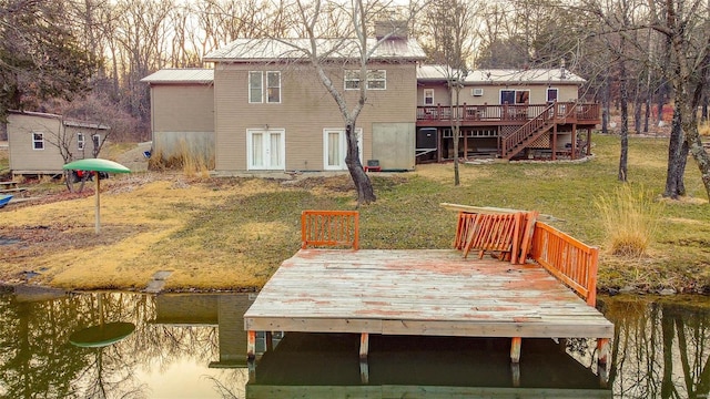 rear view of property with stairway, a yard, a deck with water view, and metal roof