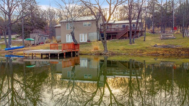 back of house featuring a deck with water view and a lawn