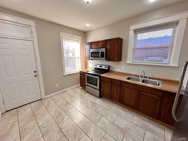 kitchen with light tile patterned floors, appliances with stainless steel finishes, light countertops, and a sink