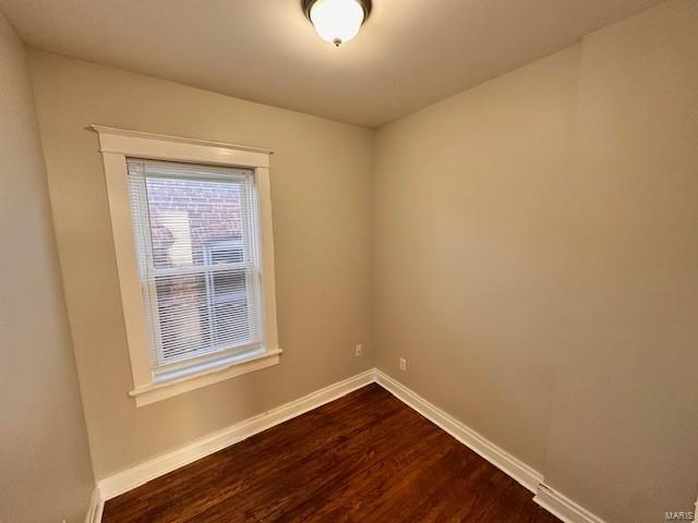 unfurnished room with dark wood finished floors and baseboards