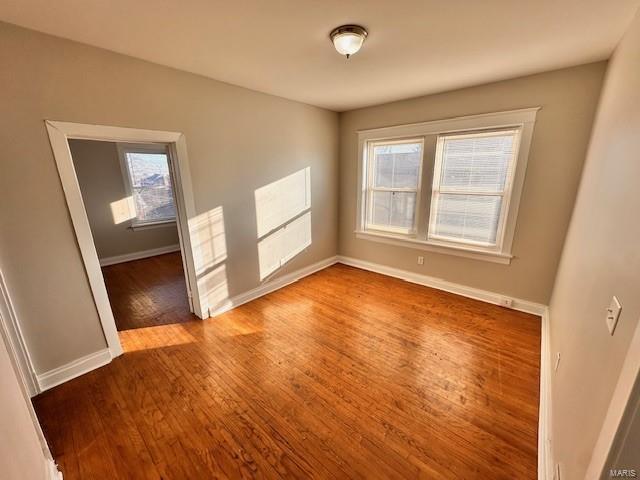 spare room with baseboards and wood finished floors