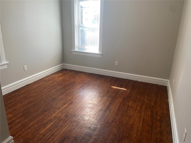 unfurnished room with baseboards and dark wood-type flooring