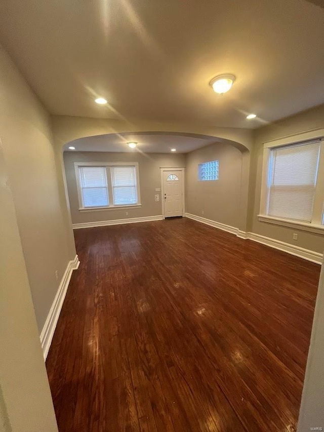 interior space with dark wood-type flooring, recessed lighting, baseboards, and arched walkways