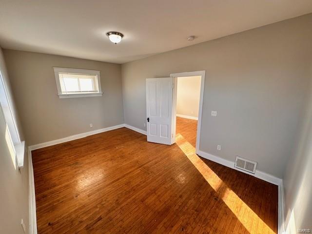 unfurnished room with visible vents, baseboards, and wood finished floors