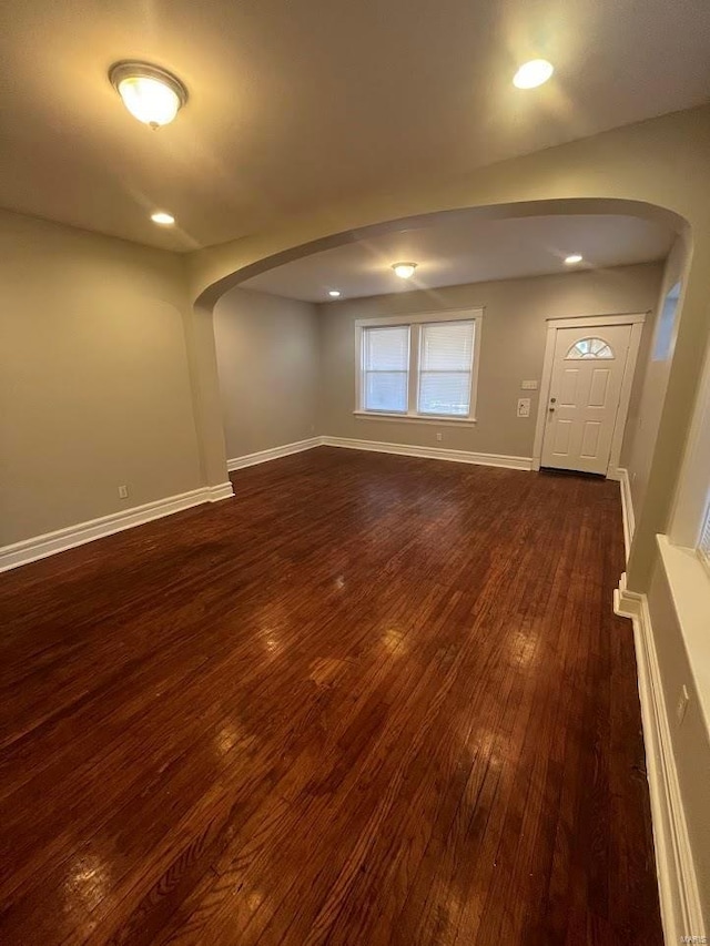 unfurnished room with recessed lighting, baseboards, arched walkways, and dark wood-style floors