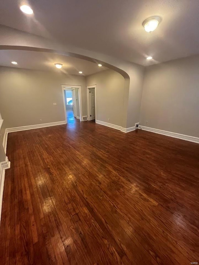 spare room featuring recessed lighting, dark wood-style floors, baseboards, and arched walkways