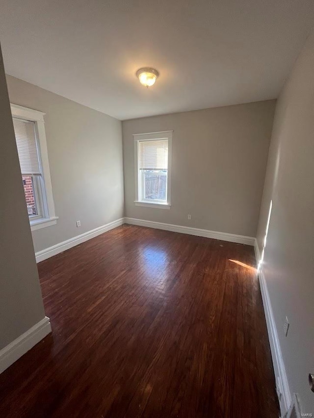 empty room featuring dark wood-type flooring and baseboards