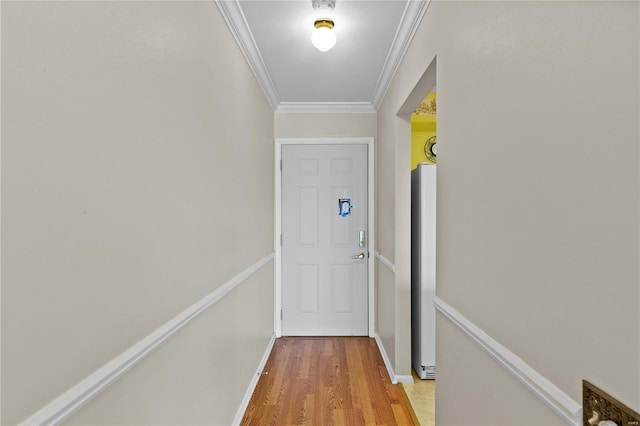 doorway to outside with crown molding, baseboards, and light wood-type flooring