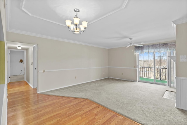 spare room featuring light wood-style flooring, light carpet, ceiling fan with notable chandelier, and ornamental molding