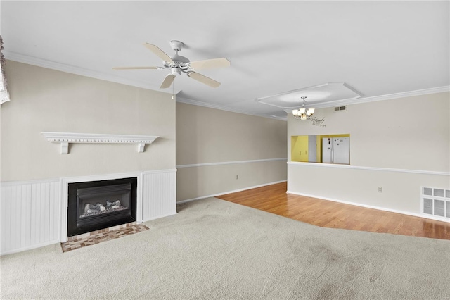 unfurnished living room with visible vents, carpet, ornamental molding, and ceiling fan with notable chandelier