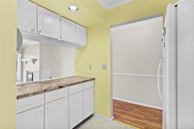 kitchen featuring baseboards, recessed lighting, freestanding refrigerator, ornamental molding, and white cabinets