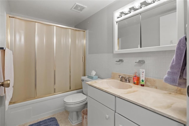 full bath with vanity, visible vents, tile walls, toilet, and combined bath / shower with glass door