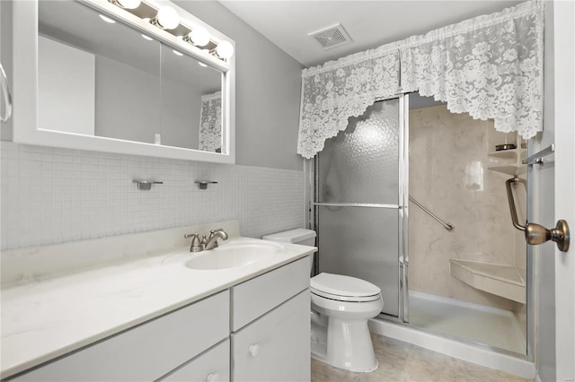 bathroom with visible vents, vanity, toilet, and a shower stall