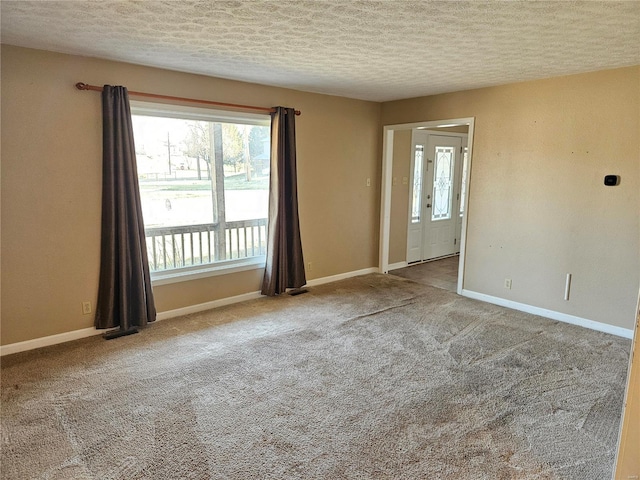 carpeted empty room with a textured ceiling and baseboards