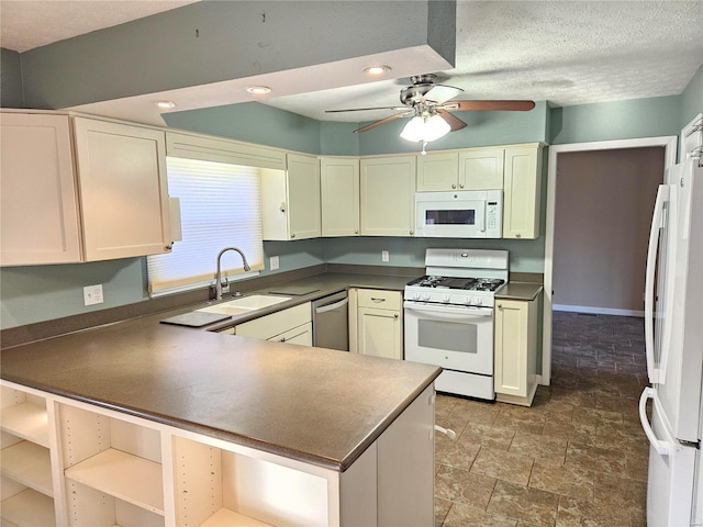 kitchen with dark countertops, white appliances, and a sink