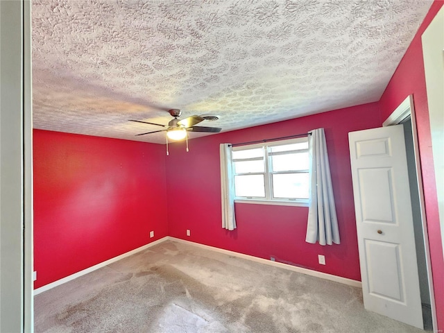 carpeted empty room featuring a ceiling fan, baseboards, and a textured ceiling