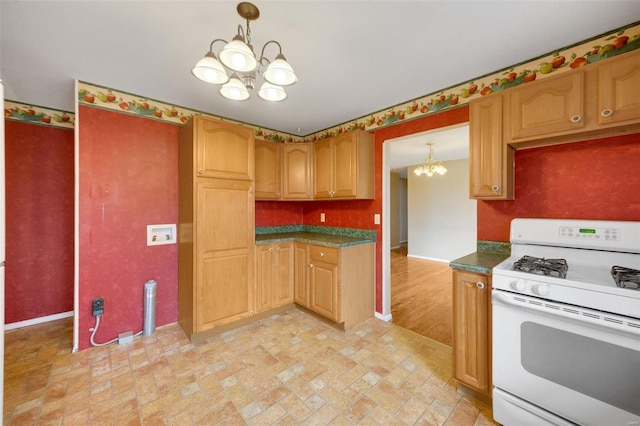 kitchen featuring baseboards, an inviting chandelier, white range with gas cooktop, dark countertops, and decorative light fixtures