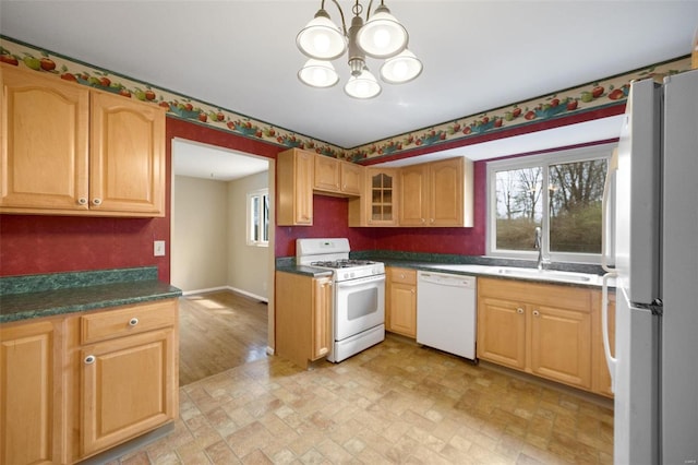 kitchen featuring a notable chandelier, a sink, dark countertops, white appliances, and glass insert cabinets