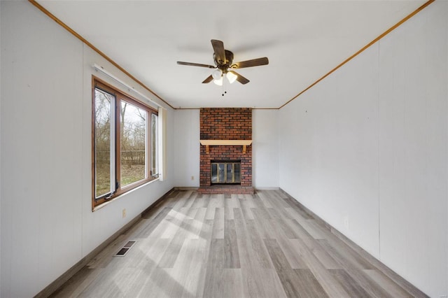 unfurnished living room featuring visible vents, light wood-style flooring, a ceiling fan, and ornamental molding