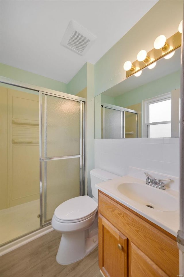 bathroom with visible vents, a shower stall, toilet, wood finished floors, and vanity