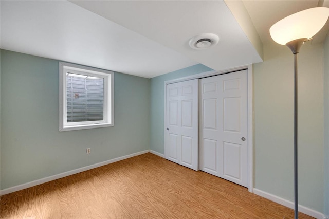 unfurnished bedroom featuring a closet, baseboards, and light wood finished floors