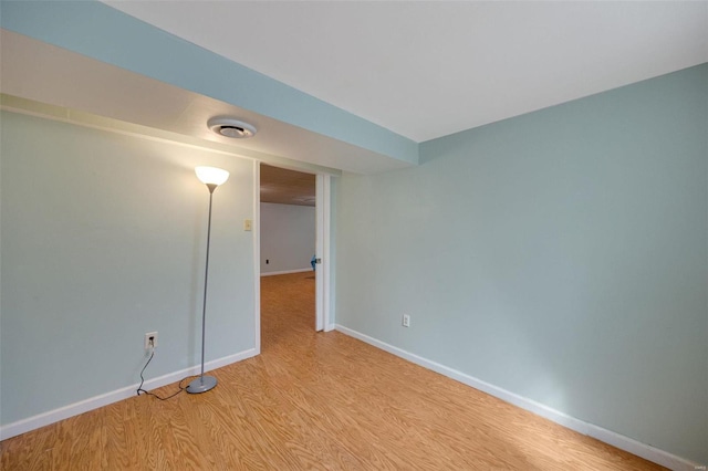 empty room with light wood finished floors, visible vents, and baseboards