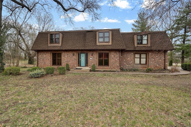 view of front of property with mansard roof, brick siding, a front yard, and a shingled roof