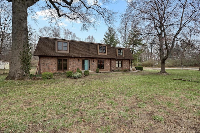 view of front of property with brick siding, mansard roof, a front lawn, and roof with shingles