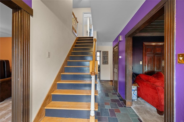 stairs featuring baseboards and stone finish floor